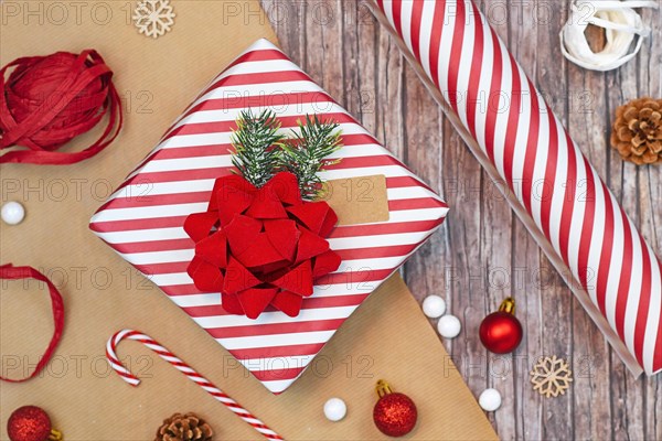 Flat lay concept for Christmas gift wrapping with beautiful red and white striped gift box with big red bow