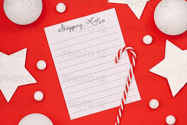 Concept for Christmas shopping with top view flat lay with empty shopping check list and seasonal decorations like candy cane