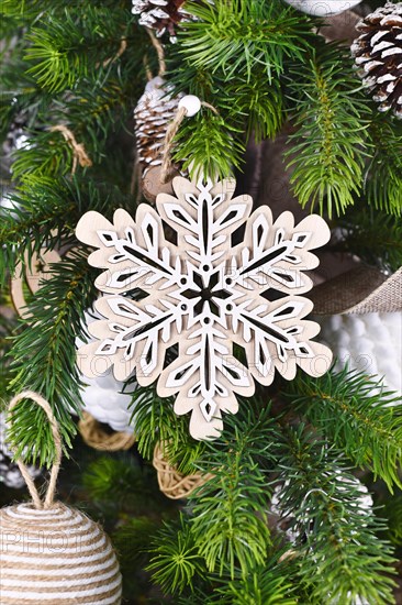 Christmas tree branch with natural wooden snowflake ornament