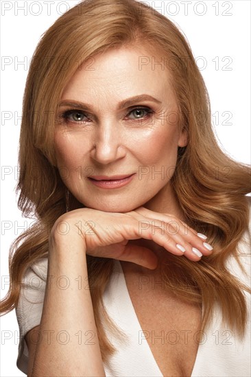 Portrait of a beautiful elderly woman in a white shirt with classic makeup and blond hair