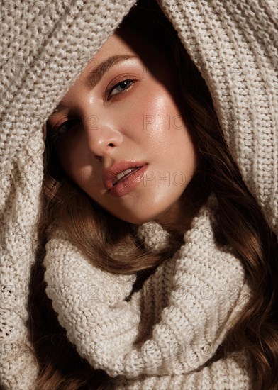 Beautiful young girl with gentle make-up in warm sweater and long straight hair. Beauty face. Studio portrait