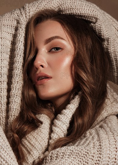 Beautiful young girl with gentle make-up in warm sweater and long straight hair. Beauty face. Studio portrait