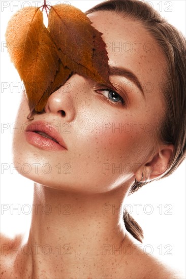 Beautiful girl with nude classic makeup and bright autumn leaves. Beauty face. Picture taken in the studio on a white background