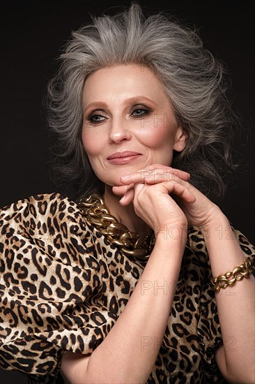 Portrait of a beautiful elderly woman in a leopard blouse with classic makeup and gray hair