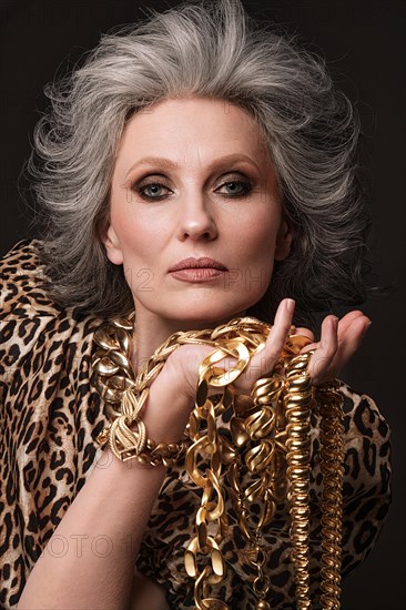 Portrait of a beautiful elderly woman in a leopard blouse with classic makeup and gray hair