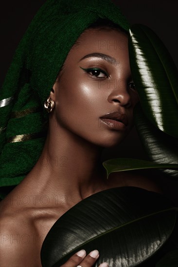 Beautiful black woman with a green towel on her head and classic make-up. Beauty face. Photo taken in the studio