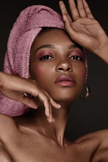 Beautiful black woman with a pink towel on her head and classic makeup. Beauty face. Photo taken in the studio