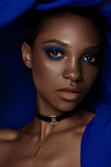 Beautiful black woman with blue fabric and classic art make-up. Beauty face. Photo taken in the studio