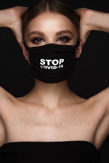 Portrait of a beautiful woman in a black mask stop covid and classic makeup. Mask mode during the covid pandemic