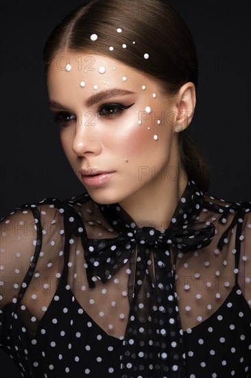 Portrait of a beautiful woman in a black dress with pearls and classic makeup. Beauty face