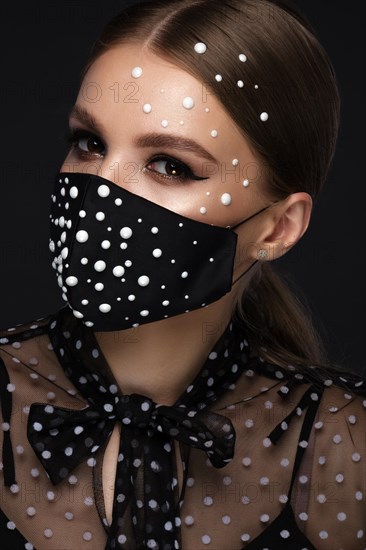 Portrait of a beautiful woman in a black mask with pearls and classic makeup. Mask mode during the covid pandemic