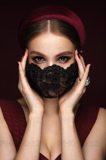 Portrait of a beautiful woman in a black lace mask and classic makeup. Mask mode during the covid pandemic