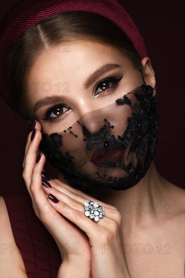 Portrait of a beautiful woman in a black lace mask and classic makeup. Mask mode during the covid pandemic