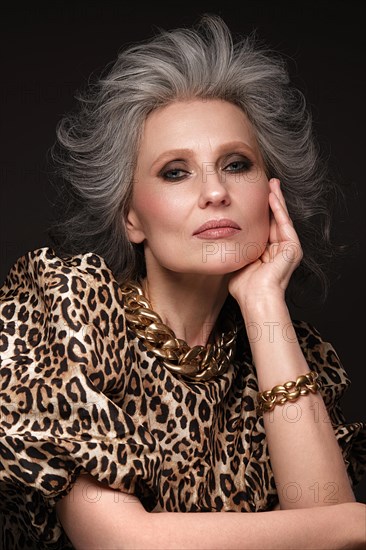 Portrait of a beautiful elderly woman in a leopard blouse with classic makeup and gray hair