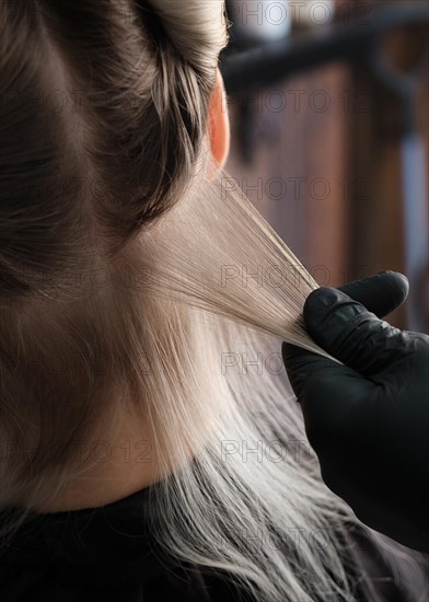 A young woman in a hairdressing salon dyes her hair blond. Hair coloring process