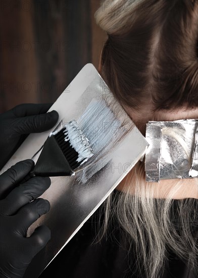 A young woman in a hairdressing salon dyes her hair blond. Hair coloring process