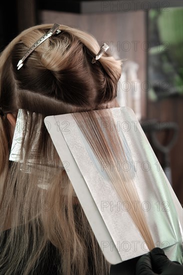 A young woman in a hairdressing salon dyes her hair blond. Hair coloring process