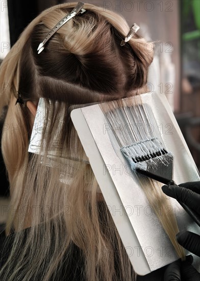 A young woman in a hairdressing salon dyes her hair blond. Hair coloring process