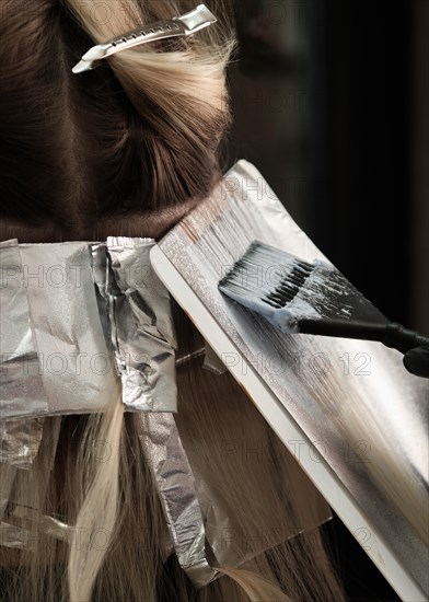 A young woman in a hairdressing salon dyes her hair blond. Hair coloring process