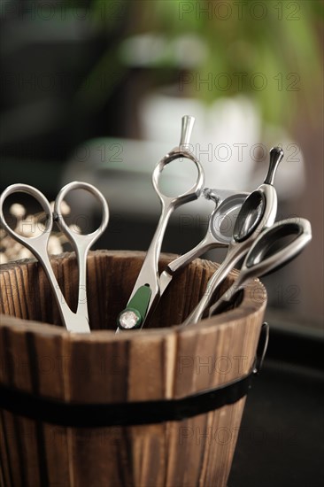 Hairdressing tools scissors close-up in a wooden vase. Close up