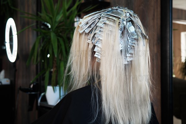 A young woman in a hairdressing salon dyes her hair blond. Hair coloring process