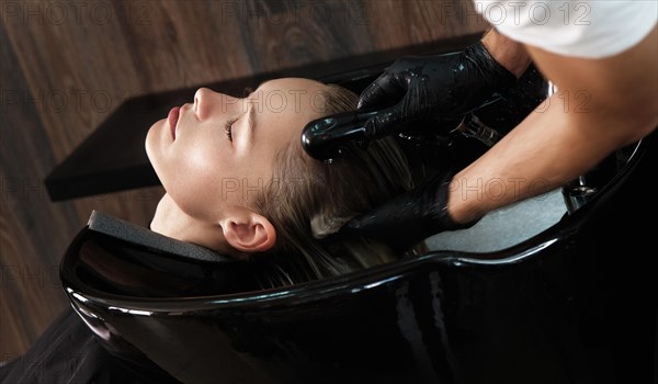 Young woman in a hairdressing salon dyes her hair blond and washing head