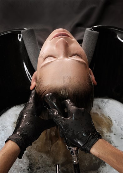 Young woman in a hairdressing salon dyes her hair blond and washing head