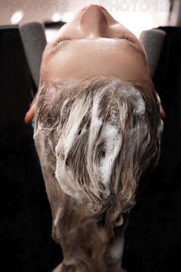 Young woman in a hairdressing salon dyes her hair blond and washing head