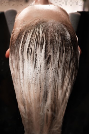 Young woman in a hairdressing salon dyes her hair blond and washing head