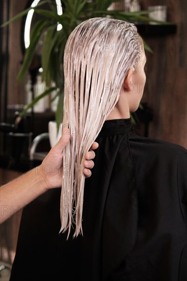 Young woman in a hairdressing salon dyes her hair blond and washing head