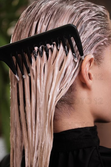 Young woman in a hairdressing salon dyes her hair blond and washing head