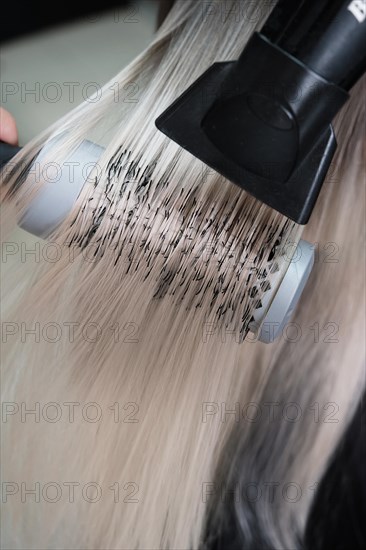 Young woman in a hairdressing salon dyes her hair blond and dries hair