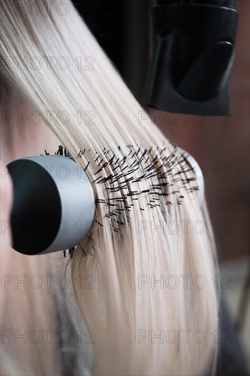 Young woman in a hairdressing salon dyes her hair blond and dries hair