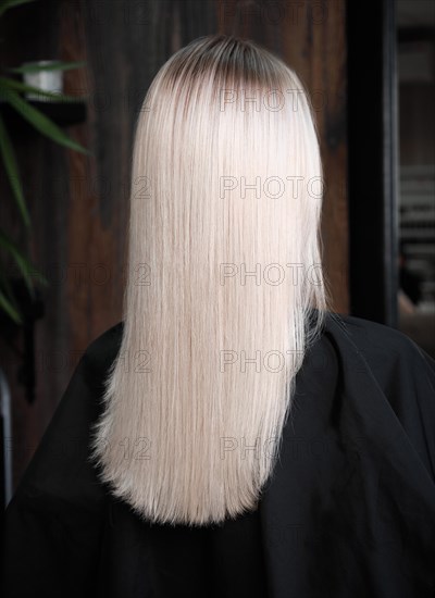 Young woman in a hairdressing salon after coloring her hair blond. beauty face and hair. Back view