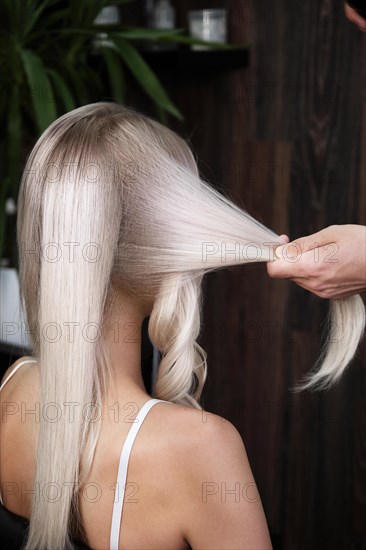 Young woman in a hairdressing salon dyes her hair blond and twists curls