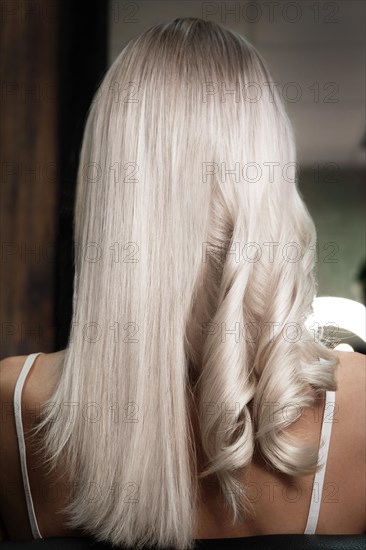 Young woman in a hairdressing salon dyes her hair blond and twists curls