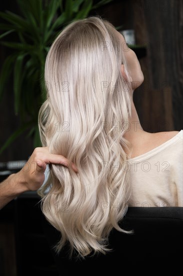 Young woman in a hairdressing salon dyes her hair blond. beauty face and hair. Back view