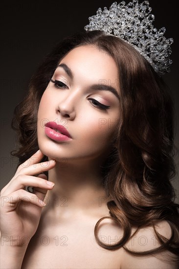 Beautiful girl with a crown in the form of a princess. Picture taken in the studio on a black background