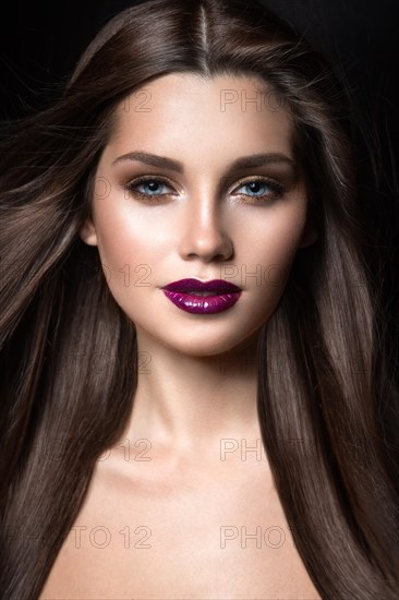 Beautiful girl with golden makeup and burgundy lips with the wind in hair. Beauty face. Picture taken in the studio on a black background