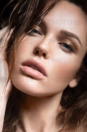 Beautiful young girl with a light natural make-up. Beauty face. Picture taken in the studio on a black background