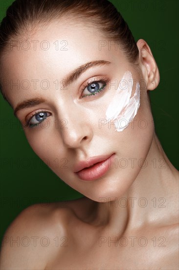 Beautiful fresh girl with cosmetic cream on the face