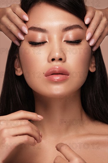 Beautiful delicate woman of oriental type with nude makeup and perfect skin. Beauty face. Spa salon