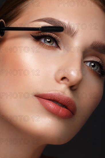 Beautiful girl with sexy lips and classic makeup with cosmetic mascara brush in hand. Beauty face. Photo taken in the studio