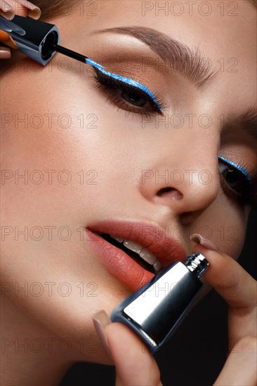 Beautiful girl with sexy lips and classic makeup with cosmetic blue eyeliner in hand. Beauty face. Photo taken in the studio