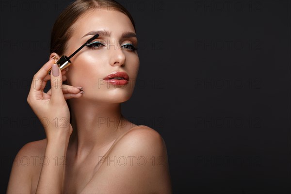 Beautiful girl with sexy lips and classic makeup with cosmetic mascara brush in hand. Beauty face. Photo taken in the studio