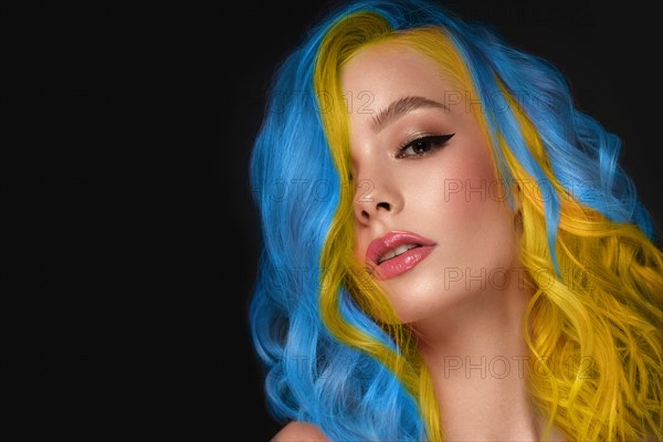 Portrait of beautiful woman with blue and yellow hair and classic make up and hairstyle