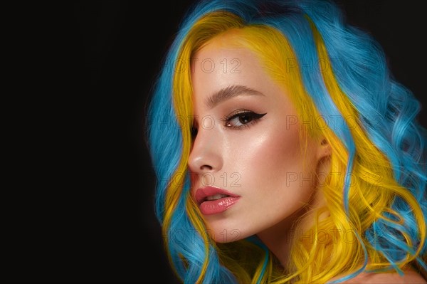 Portrait of beautiful woman with blue and yellow hair and classic make up and hairstyle