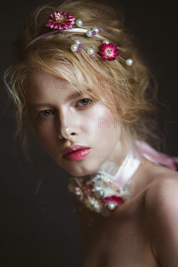 Beautiful blond fashion girl with flowers on the neck and in her hair