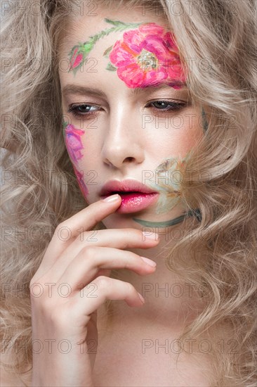 Beautiful blond girl with tresses and a floral pattern on the face. Beauty flowers. Portrait shot in studio