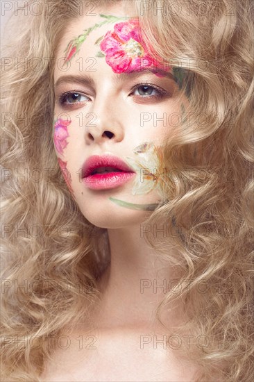 Beautiful blond girl with tresses and a floral pattern on the face. Beauty flowers. Portrait shot in studio